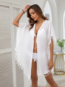 Detail of white beach cover-up with fringe trim and hollow-out crochet embroidery