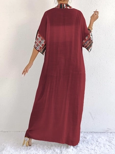 Rear view of a long burgundy sun protection cardigan with ethnic print trims and loose fit