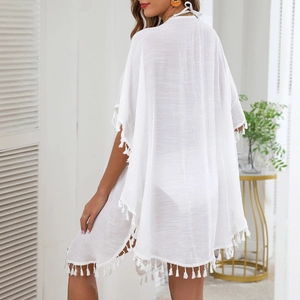 Close-up of white semi-transparent beach cover-up featuring fringe details and textured fabric
