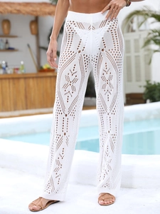Detail shot of white crochet beach pants featuring intricate hollow geometric patterns