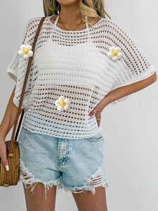Close-up of white crochet top featuring 3D floral accents and hollow knit texture