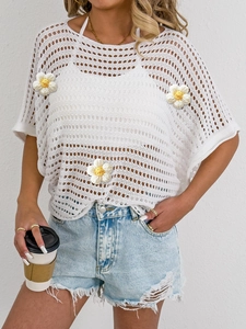 Close-up of white crochet hollow-out top featuring 3D floral appliqués and textured knit