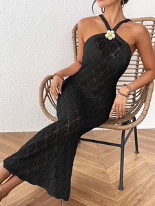 Detail of black crochet halter dress featuring a 3D white floral accent at the neckline