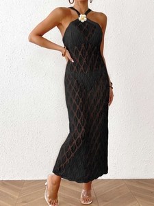 Detail of black crochet maxi dress featuring a white sunflower on the halter neckline