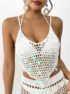 Détail du haut de plage au crochet blanc avec paillettes irisées et motifs tricotés à la main
