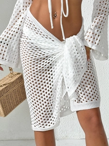 Close-up of white crochet beach sarong featuring geometric hollow knit patterns and waist tie