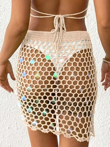 Detail of beige crochet mini skirt showing knit texture and colorful sequin accents
