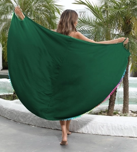 Dettaglio del pareo verde scuro con bordi a pompon colorati mostrato a bordo piscina all'aperto