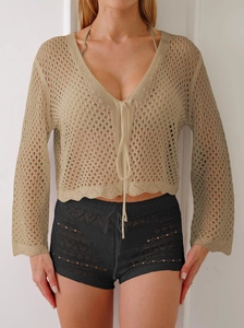 Dettaglio del cardigan beige in maglia crochet con scollo a V e chiusura con lacci