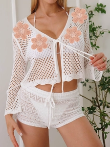 Dettaglio del set da spiaggia in maglia bianca con ricami floreali e trama a rete aperta