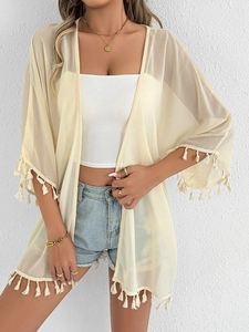 Detail of bohemian light yellow chiffon cover-up featuring white fringe tassels on the hem
