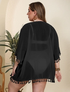 Detail showing the hemline fringe and lightweight sheer fabric of this black beach cover-up