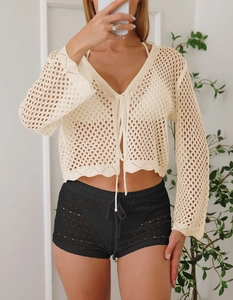 Dettaglio della trama a maglia del cardigan all'uncinetto crema e pantaloncini da spiaggia