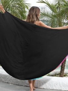 Sarong nero da spiaggia con pompon colorati mostrato da una modella in un resort