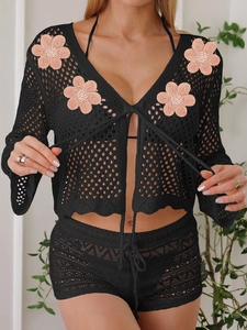 Dettaglio della maglia nera all'uncinetto con fiori 3D rosa sulla manica del copricostume