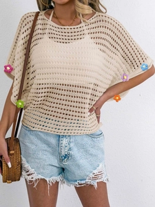 Detail of colorful crochet flowers and openwork knit on beige bohemian top sleeve