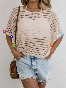 Detail of crochet blouse featuring colorful handmade 3D floral accents on cuffs
