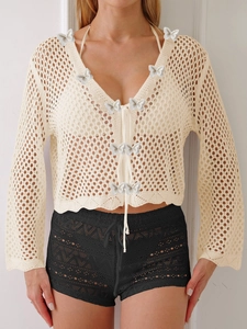 Détail du cardigan au crochet crème avec col en V à nouer et papillons en 3D
