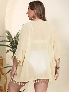 Detail of cream chiffon beach cover-up featuring elegant fringe trim and semi-sheer fabric