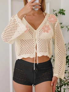 Dettaglio cardigan beige all'uncinetto con ricamo floreale 3D rosa e lacci sul davanti
