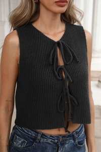 Primo piano del top nero in maglia a costine con tre fiocchi frontali e design a traforo