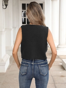 Back view of a cropped dark grey knit top paired with slim-fit blue jeans in a white hallway