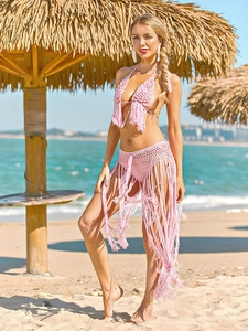 Detail of pink crochet bikini with long fringe hem on a sunny tropical beach