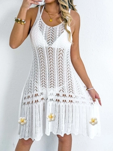 Detail of white crochet knit beach dress featuring hollow patterns and floral appliques
