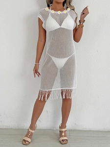 Détail d'une robe de plage blanche en crochet avec fleurs jaunes et ourlet à franges