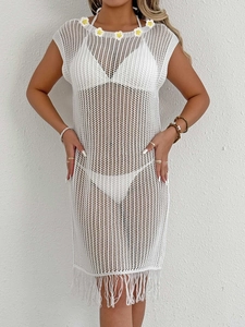 Détail d'une robe de plage en maille crochet avec appliqués marguerites et franges