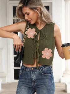 Gros plan détaillé d'un gilet tricoté vert foncé avec broderie florale et liens à nouer