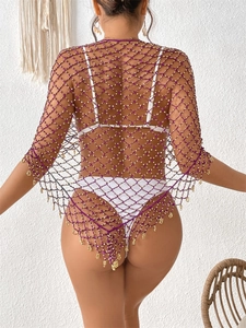 Detail von lila Netz-Strandmode mit weißen Perlen und metallischen Fransen am Saum