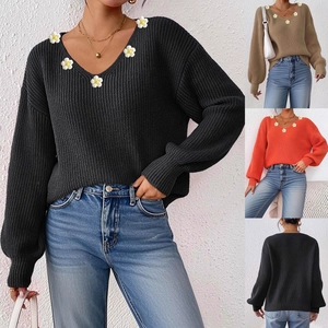 Detailsicht auf weiße Blumenstickereien an einem strukturierten V-Ausschnitt Strickpullover