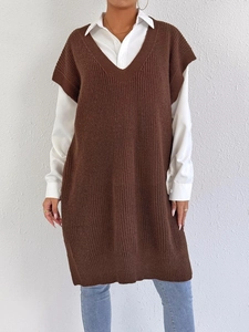 Dettaglio di un gilet in maglia marrone con scollo a V sopra una camicia bianca lunga