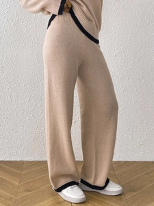 Dettaglio dei pantaloni in maglia a gamba larga a vita alta con bordi neri a contrasto