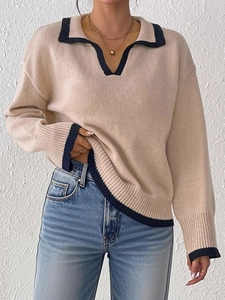 Detail of soft apricot knit sweater with navy contrast trim on polo collar and sleeve cuffs