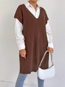 Dettaglio del gilet in maglia marrone con scollo a V, spacchi laterali e camicia bianca