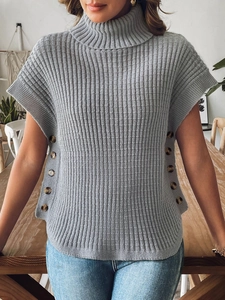 Dettaglio del gilet in maglia grigia a dolcevita con bottoni decorativi e trama a coste