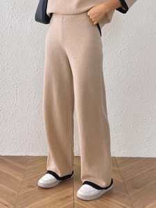 Dettaglio ravvicinato del drappeggio e della trama dei pantaloni beige in maglia a gamba larga