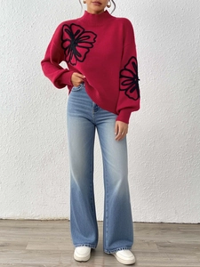Close-up of red high neck sweater with black floral embroidery and lantern sleeves