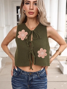Gilet en tricot vert foncé avec fleurs au crochet roses et liens à nouer
