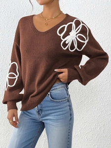 Detail of white 3D floral embroidery on dark brown V-neck knitted sweater sleeve