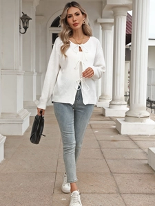Close-up of white knit cardigan featuring elegant triple bow-tie front closures