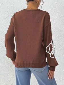 Detail of white flower embroidery on brown knit sweater sleeves with a relaxed fit style
