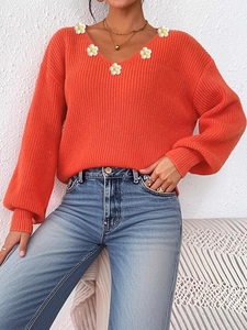 Nahaufnahme von orangefarbenem V-Ausschnitt Strickpullover mit weißen Gänseblümchen