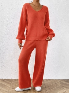 Detail of coral orange knit set featuring vertical ribbed texture and wide-leg trousers