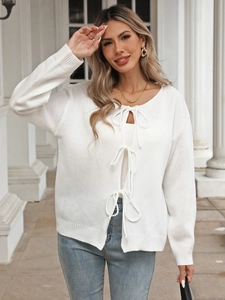 Detail of white knit cardigan with elegant ribbon bow ties and soft textured finish