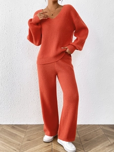 Macro detail of the orange knit texture on the V-neck top and wide-leg trousers set
