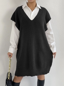 Dettaglio dell'abito a gilet in maglia nera con scollo a V profondo sopra camicia