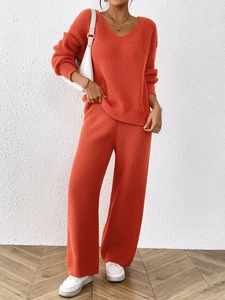 Detail of orange knit set featuring V-neck loose sweater and matching wide-leg pants